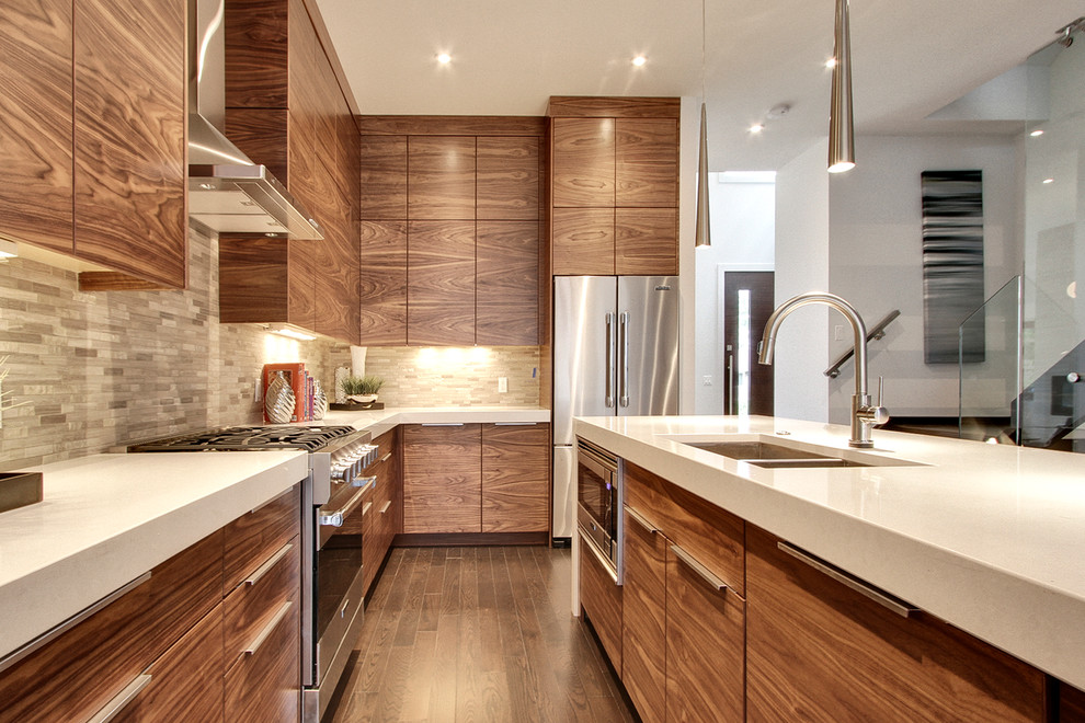 This is an example of a mid-sized contemporary l-shaped open plan kitchen in Calgary with flat-panel cabinets, medium wood cabinets, grey splashback, stainless steel appliances, stone tile splashback, a double-bowl sink, quartzite benchtops, dark hardwood floors, with island and brown floor.
