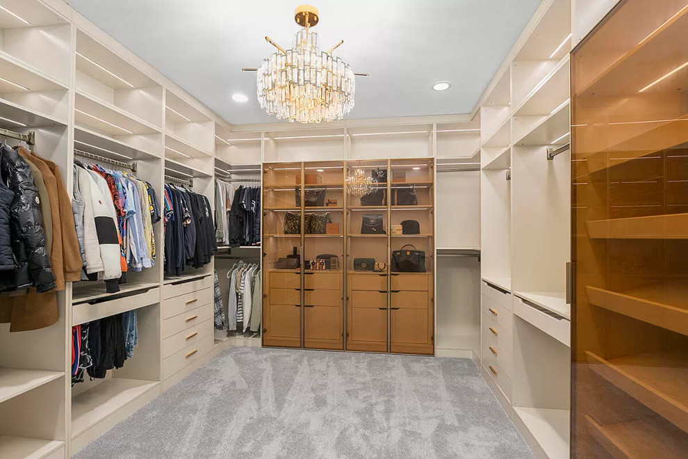 Inspiration for an expansive country walk-in wardrobe in Grand Rapids with glass-front cabinets, light wood cabinets and carpet.