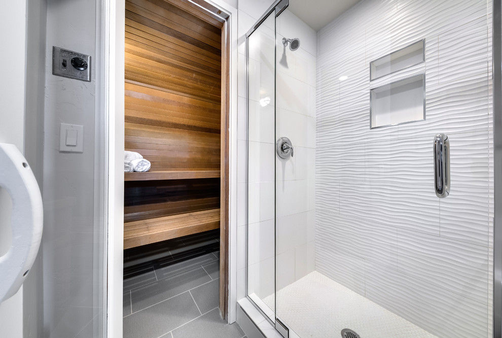 This is an example of a mid-sized contemporary bathroom in Boise with shaker cabinets, dark wood cabinets, a drop-in tub, an alcove shower, a two-piece toilet, white tile, ceramic tile, white walls, ceramic floors, with a sauna, an undermount sink, engineered quartz benchtops, grey floor and a hinged shower door.