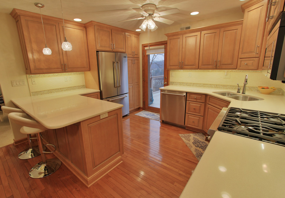 Eat-in kitchen - mid-sized medium tone wood floor eat-in kitchen idea with an undermount sink, medium tone wood cabinets, quartzite countertops, beige backsplash, ceramic backsplash and stainless steel appliances