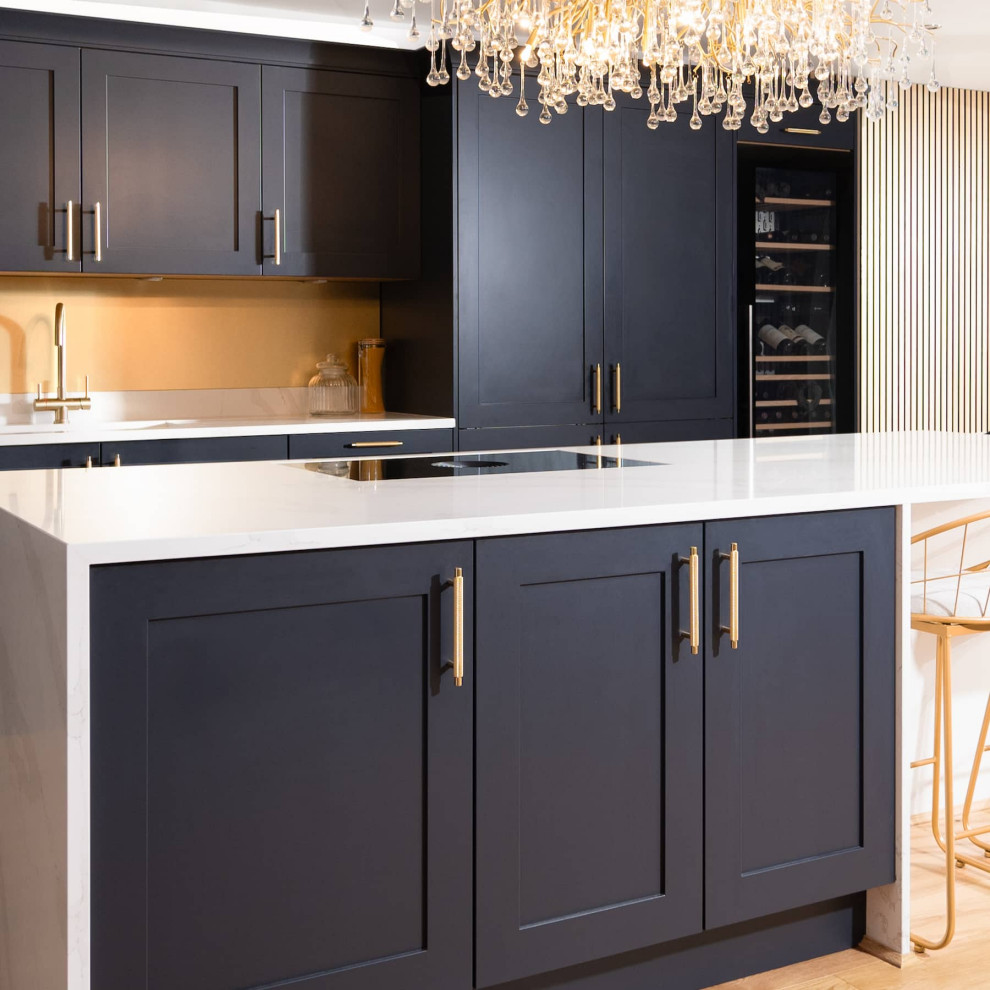 Design ideas for a large traditional l-shaped open plan kitchen in Hertfordshire with a submerged sink, shaker cabinets, blue cabinets, quartz worktops, ceramic splashback, stainless steel appliances, light hardwood flooring, an island, brown floors, white worktops and feature lighting.