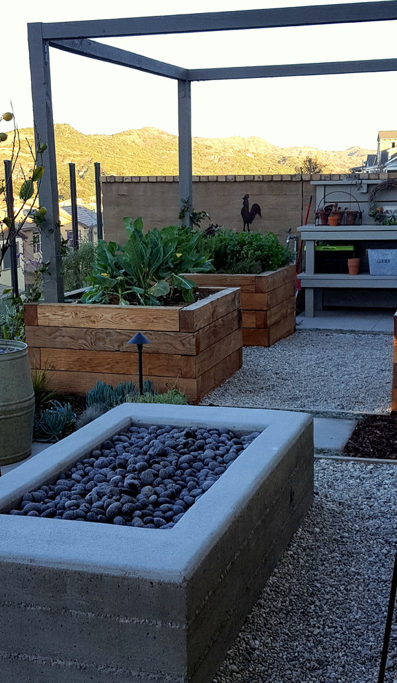 This is an example of a small country backyard full sun xeriscape in Los Angeles with a vegetable garden and concrete pavers.