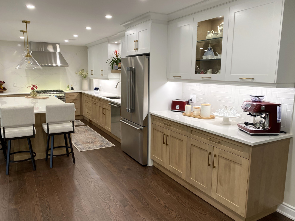 Mid-sized transitional l-shaped medium tone wood floor and brown floor eat-in kitchen photo in Toronto with an undermount sink, shaker cabinets, white cabinets, quartz countertops, white backsplash, quartz backsplash, stainless steel appliances, an island and white countertops