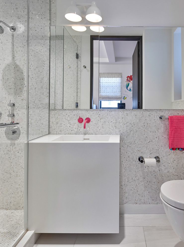 Photo of a small contemporary family bathroom in New York with white cabinets, a walk-in shower, a one-piece toilet, white tiles, mosaic tiles, marble flooring, an integrated sink, solid surface worktops, white floors, a hinged door, white worktops, a single sink and a floating vanity unit.
