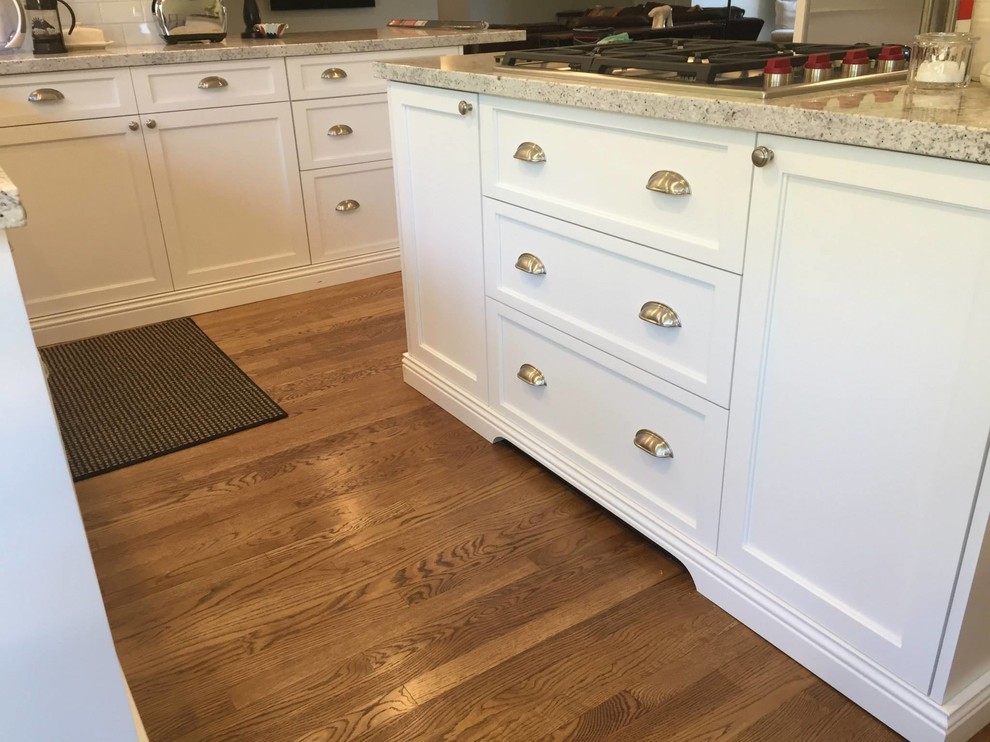 Example of a large transitional medium tone wood floor kitchen design in Phoenix with an undermount sink, shaker cabinets, white cabinets, granite countertops, white backsplash, subway tile backsplash, stainless steel appliances and an island