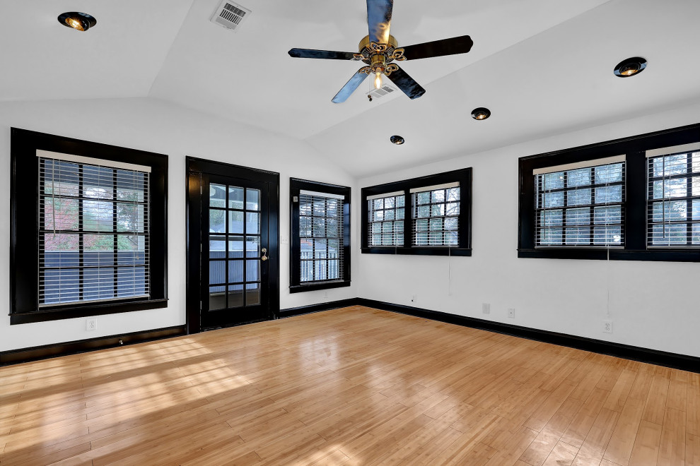 Immagine di un grande studio yoga minimalista con pareti bianche, pavimento in bambù, pavimento giallo e soffitto a volta