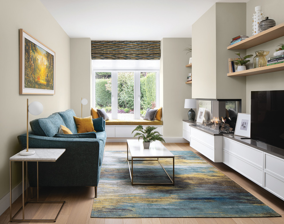 Design ideas for a large modern enclosed living room in Dublin with a library, green walls, medium hardwood floors, a two-sided fireplace, a plaster fireplace surround and a freestanding tv.