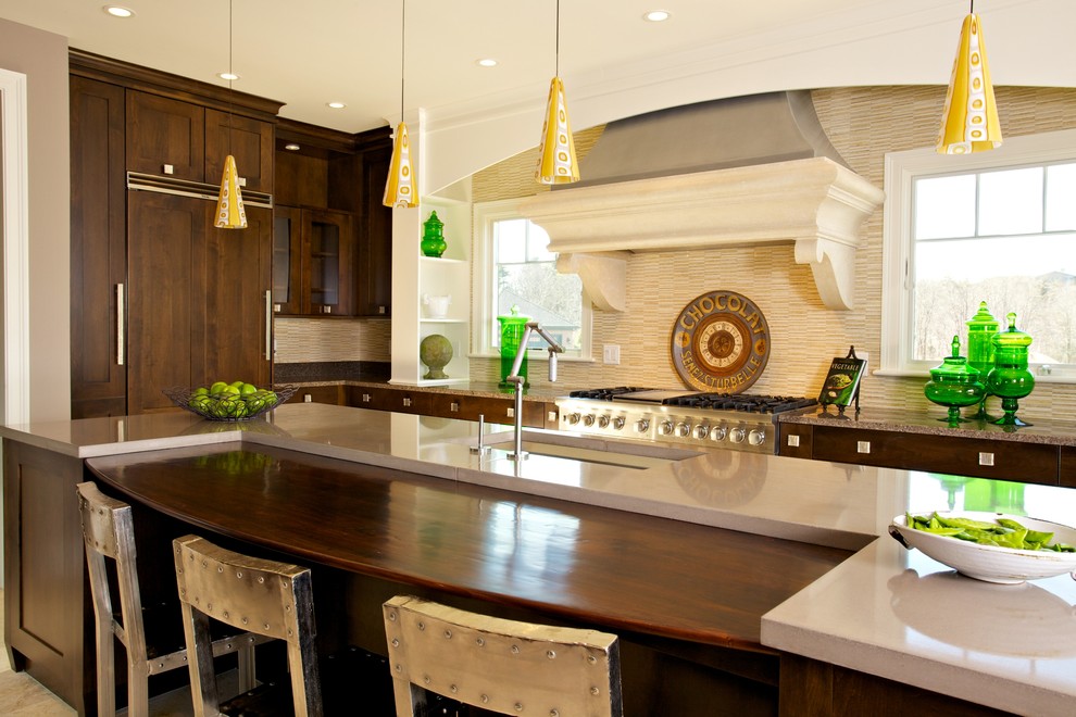 Inspiration for a transitional l-shaped travertine floor eat-in kitchen remodel in Boston with recessed-panel cabinets, dark wood cabinets, concrete countertops, beige backsplash, stone tile backsplash, paneled appliances, gray walls, an island and an undermount sink