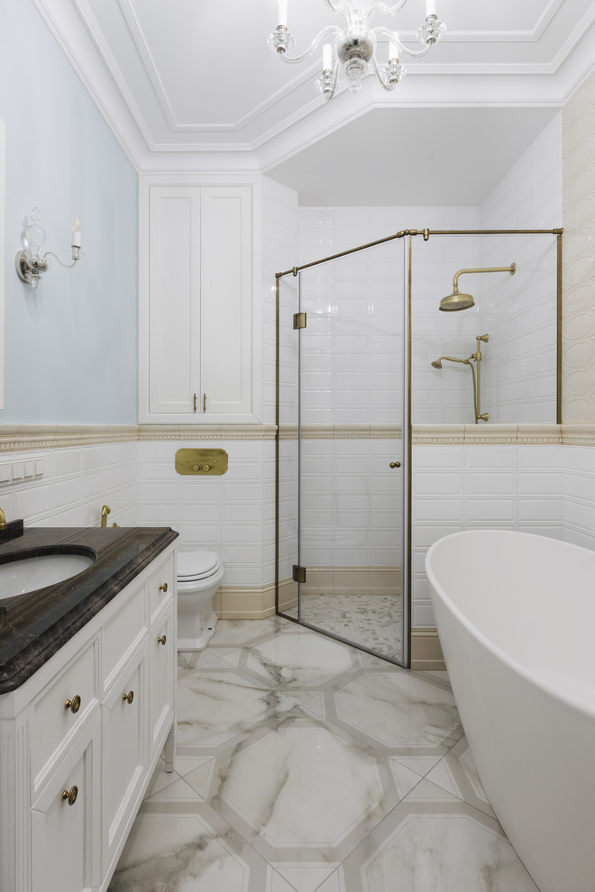 Design ideas for a traditional master bathroom in Saint Petersburg with recessed-panel cabinets, white cabinets, a freestanding tub, a corner shower, a two-piece toilet, white tile, blue walls, an undermount sink, beige floor, a hinged shower door and brown benchtops.