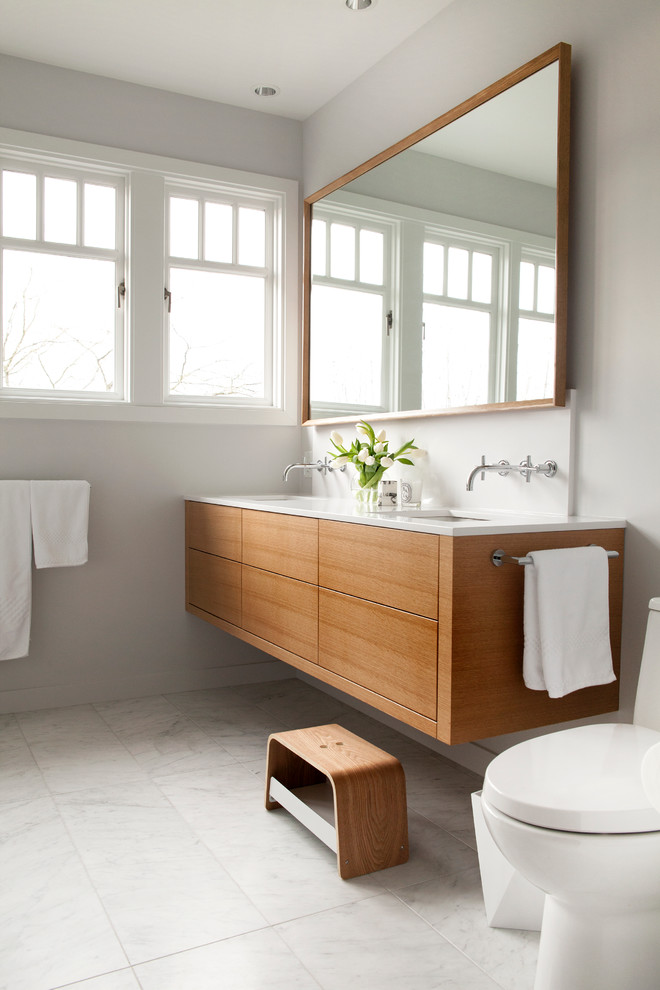 Design ideas for a mid-sized modern kids bathroom in Vancouver with furniture-like cabinets, light wood cabinets, an undermount tub, a corner shower, a one-piece toilet, white tile, stone tile, white walls, marble floors, an undermount sink and quartzite benchtops.