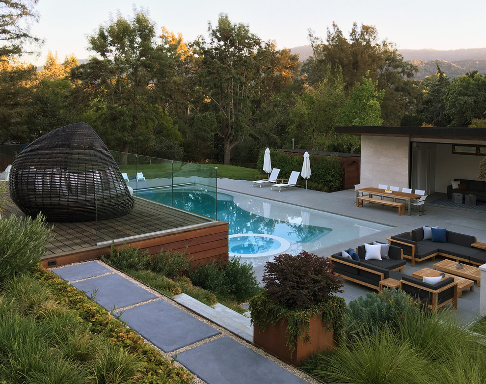 Photo of a contemporary backyard custom-shaped lap pool in San Francisco with a hot tub and concrete pavers.