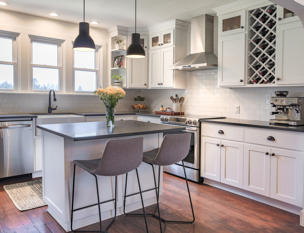 Design ideas for a mid-sized country eat-in kitchen in Portland with a farmhouse sink, shaker cabinets, white cabinets, quartz benchtops, white splashback, subway tile splashback, stainless steel appliances, medium hardwood floors, with island and brown floor.