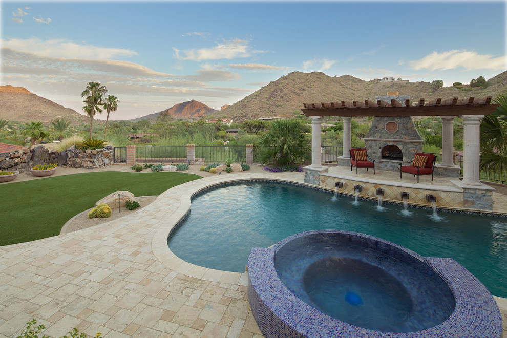 This is an example of a large mediterranean backyard custom-shaped natural pool in Phoenix with a pool house and natural stone pavers.