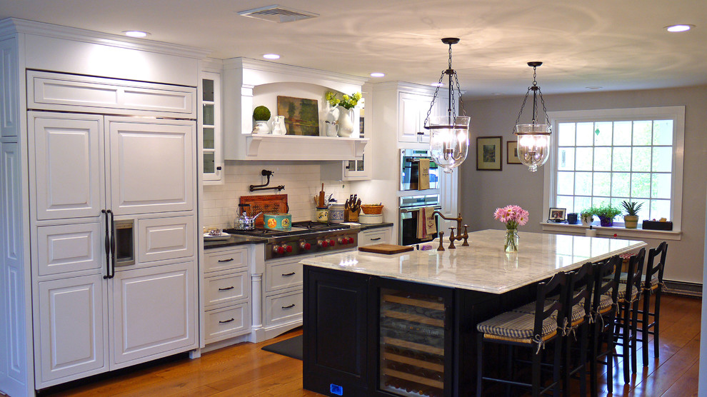 This is an example of a large country single-wall eat-in kitchen in Boston with a farmhouse sink, white cabinets, quartzite benchtops, white splashback, ceramic splashback, panelled appliances, medium hardwood floors, with island and raised-panel cabinets.