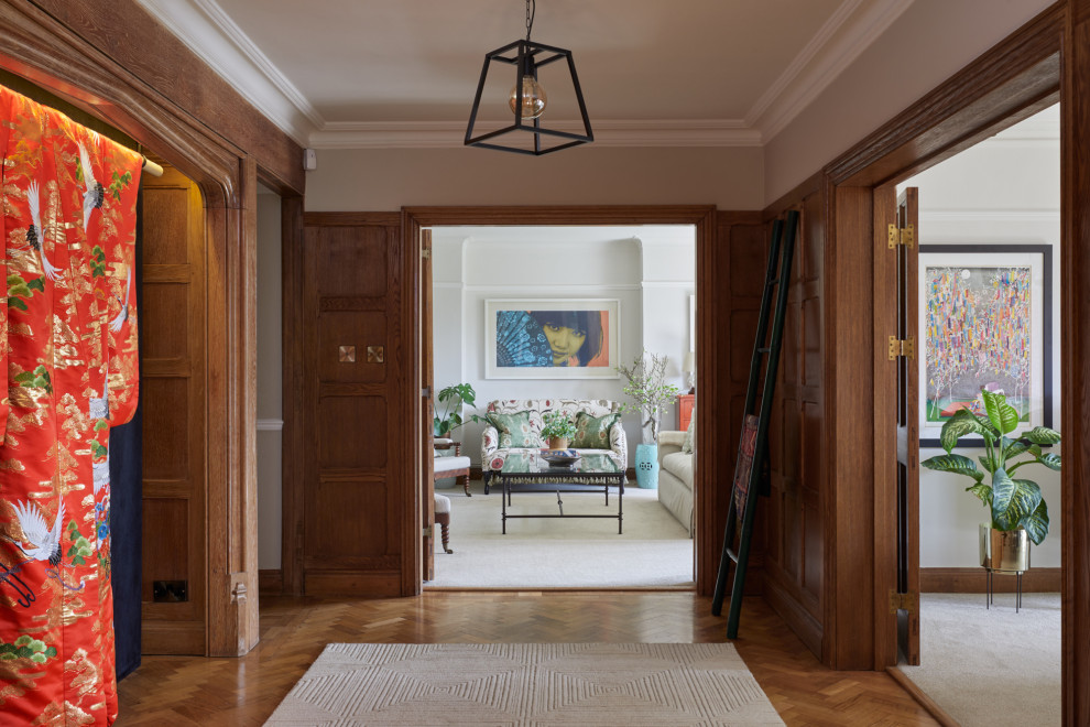 This is an example of a mid-sized transitional hallway in Hertfordshire with grey walls, medium hardwood floors, brown floor and panelled walls.