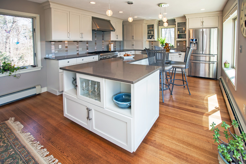 Eat-in kitchen - large transitional l-shaped medium tone wood floor eat-in kitchen idea in Boston with an undermount sink, shaker cabinets, white cabinets, quartz countertops, gray backsplash, glass sheet backsplash, stainless steel appliances and an island