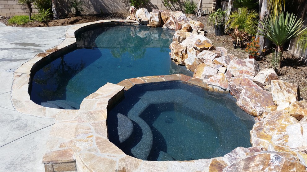 This is an example of a small transitional backyard custom-shaped lap pool in Los Angeles with a hot tub and stamped concrete.