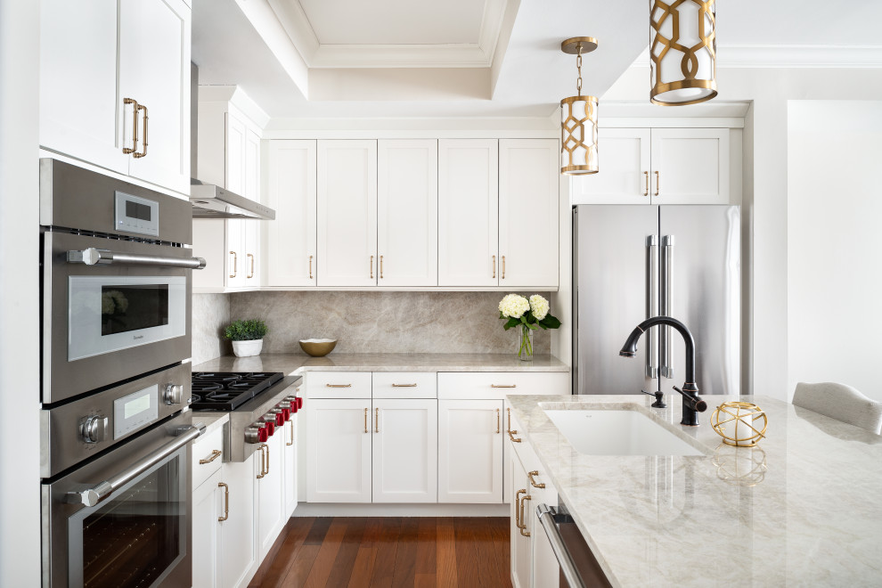 This is an example of a small transitional l-shaped eat-in kitchen in New York with an undermount sink, shaker cabinets, white cabinets, quartzite benchtops, stainless steel appliances, medium hardwood floors, with island, brown floor and beige benchtop.