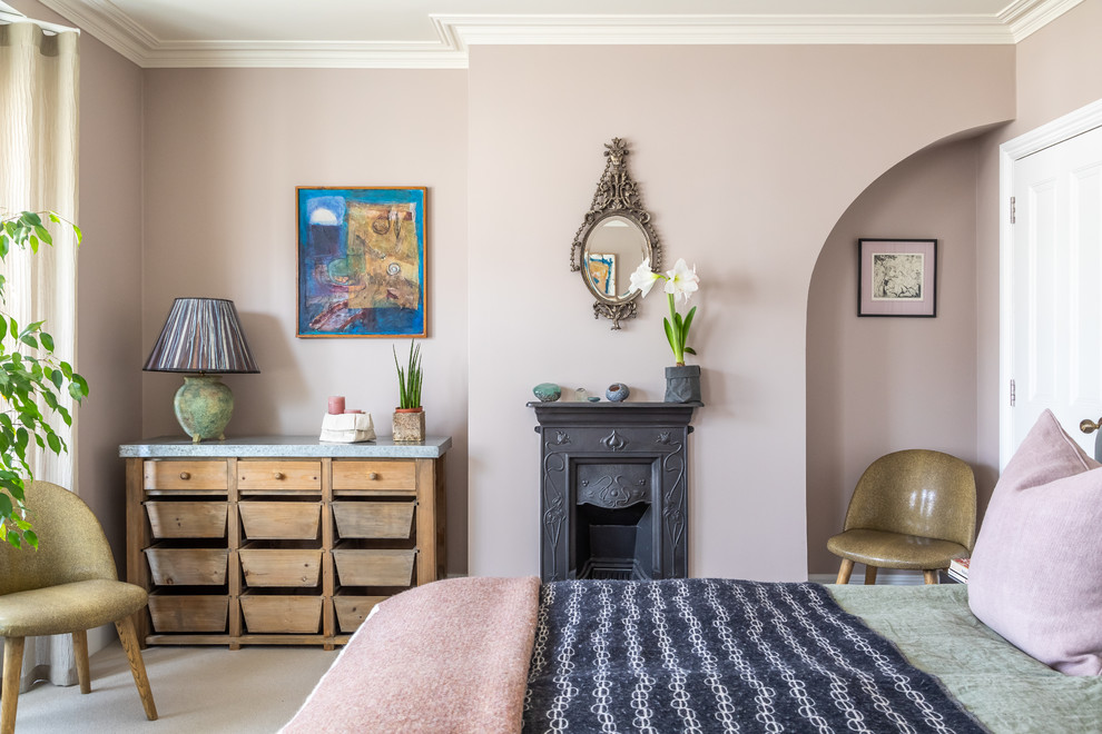 Photo of an eclectic master bedroom in Cambridgeshire with pink walls, carpet, a standard fireplace, a metal fireplace surround and grey floor.