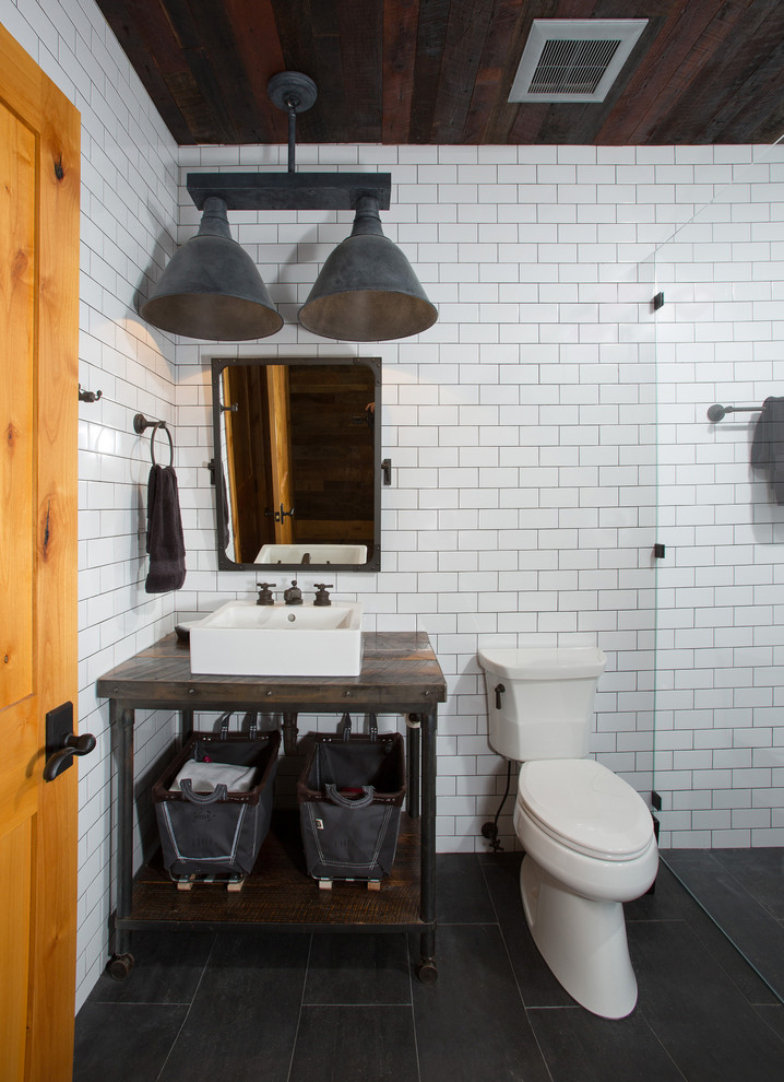 Mid-sized country 3/4 bathroom in DC Metro with a curbless shower, a one-piece toilet, white tile, subway tile, white walls, a vessel sink, wood benchtops, black floor, a hinged shower door, porcelain floors and open cabinets.