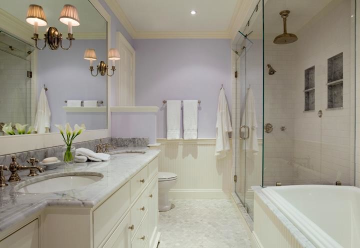 Photo of a large traditional master bathroom with recessed-panel cabinets, white cabinets, a drop-in tub, a corner shower, a one-piece toilet, white tile, subway tile, purple walls, marble floors, an undermount sink, marble benchtops, grey floor and a hinged shower door.