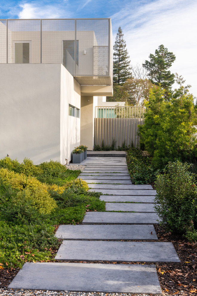 Foto di un grande giardino minimalista esposto in pieno sole davanti casa in primavera con ghiaia e recinzione in legno