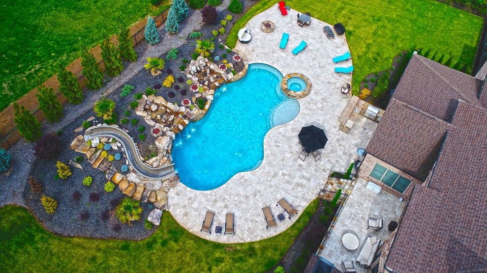 Design ideas for a large backyard custom-shaped natural pool with a water slide and decking.