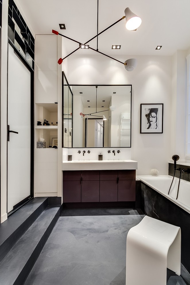 This is an example of a large contemporary master bathroom in Paris with marble benchtops, black floor, a hinged shower door, white benchtops, white walls, concrete floors, beaded inset cabinets, black cabinets, an undermount tub, a wall-mount toilet, white tile, mirror tile and a trough sink.