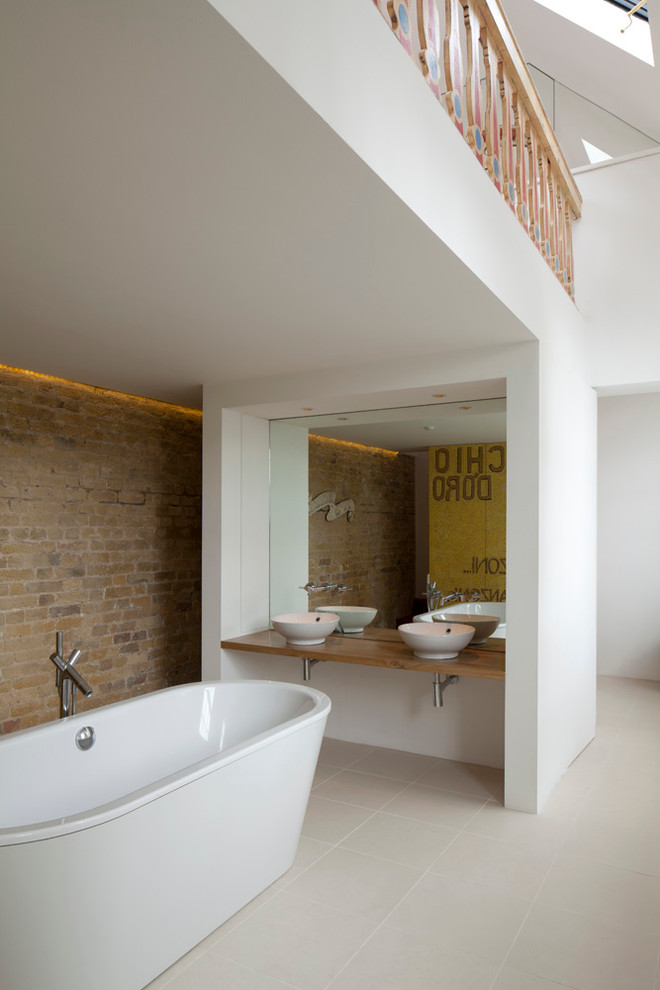 Inspiration for a contemporary bathroom in London with a vessel sink, a freestanding tub and wood benchtops.