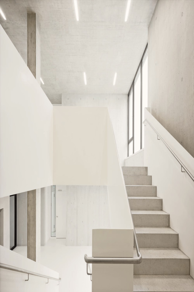 Inspiration pour un très grand couloir minimaliste avec un mur blanc, un sol en terrazzo et un sol blanc.