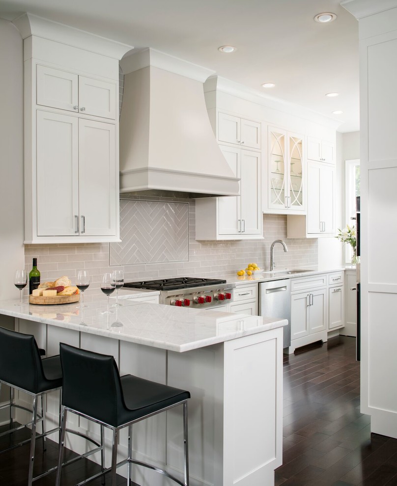 Small transitional l-shaped eat-in kitchen in DC Metro with an undermount sink, white cabinets, marble benchtops, grey splashback, glass tile splashback, stainless steel appliances, dark hardwood floors, a peninsula and shaker cabinets.