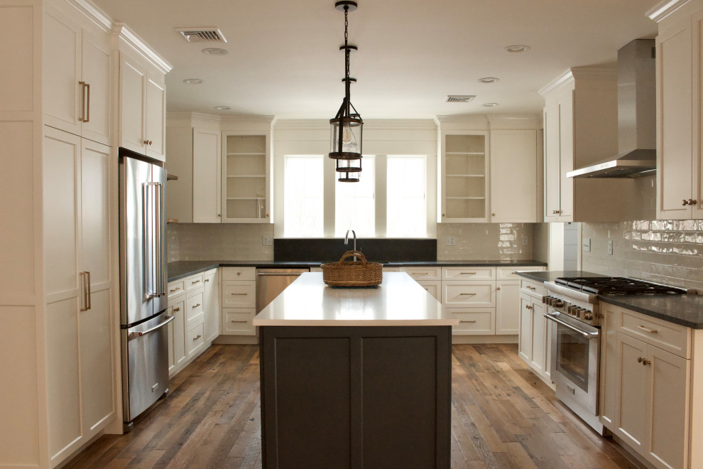 Eat-in kitchen - large farmhouse u-shaped medium tone wood floor and brown floor eat-in kitchen idea in New York with an undermount sink, shaker cabinets, white cabinets, quartz countertops, beige backsplash, porcelain backsplash, stainless steel appliances, an island and white countertops