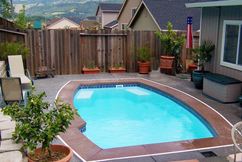 Inspiration for a mid-sized traditional backyard custom-shaped pool in Other with concrete slab.