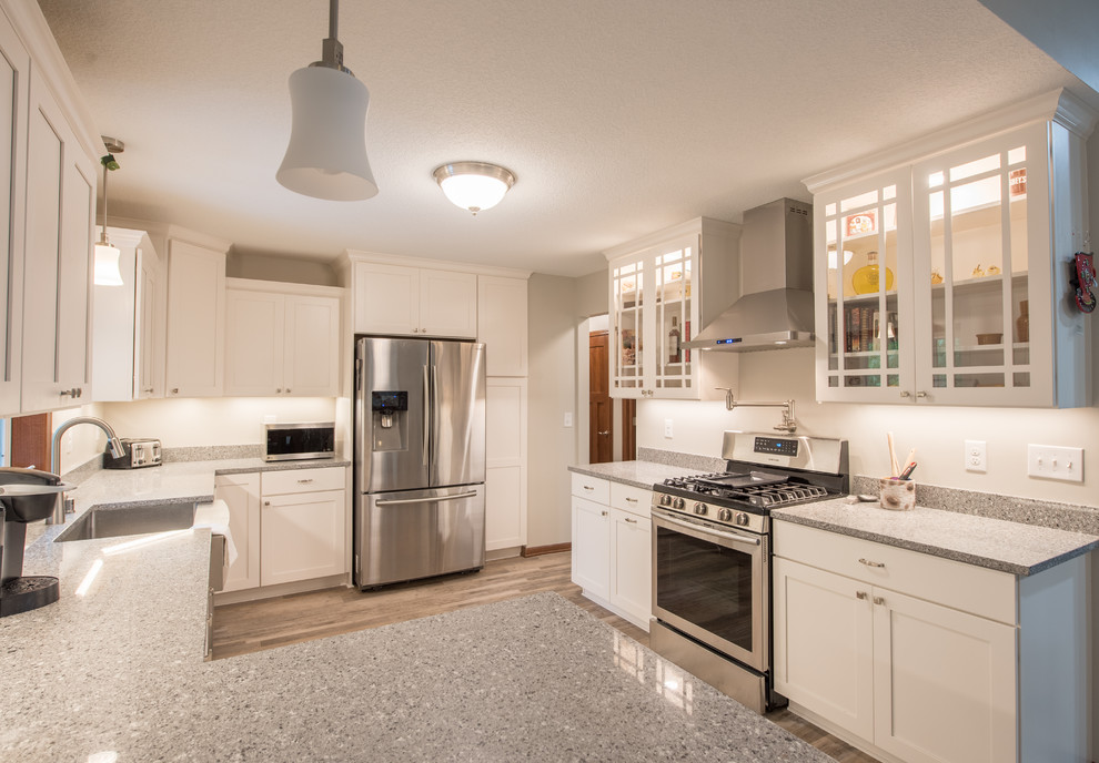 Inspiration for a large transitional u-shaped light wood floor and brown floor enclosed kitchen remodel in Minneapolis with a farmhouse sink, shaker cabinets, white cabinets, granite countertops, stainless steel appliances, a peninsula and gray countertops