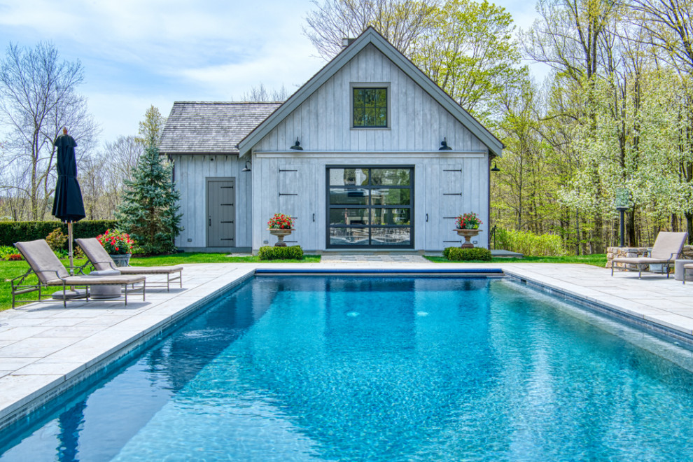 Immagine di una grande piscina naturale chic rettangolare dietro casa con una dépendance a bordo piscina e pavimentazioni in pietra naturale