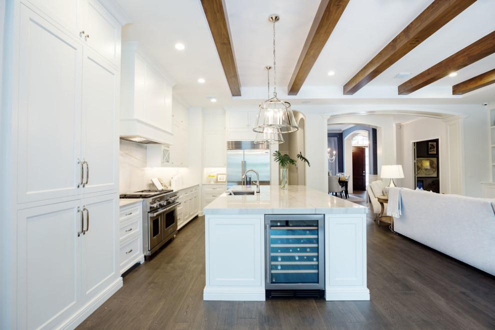 Inspiration for a mid-sized transitional single-wall eat-in kitchen in Orlando with recessed-panel cabinets, white cabinets, quartz benchtops, grey splashback, engineered quartz splashback, stainless steel appliances, medium hardwood floors, with island, brown floor, grey benchtop, exposed beam and a single-bowl sink.