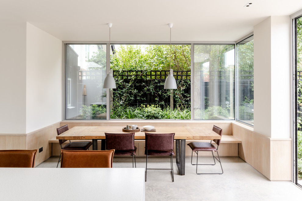 Idées déco pour une salle à manger moderne de taille moyenne avec une banquette d'angle, un mur blanc, sol en béton ciré et un sol gris.