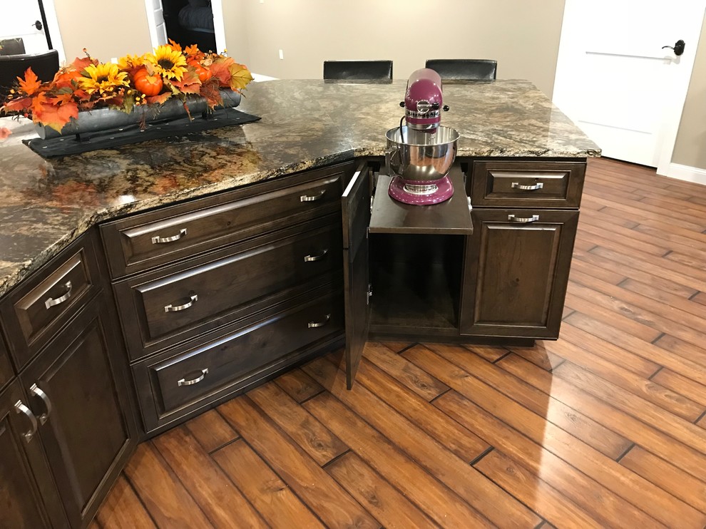 Open concept kitchen - large traditional galley dark wood floor and brown floor open concept kitchen idea with raised-panel cabinets, granite countertops, stainless steel appliances, an undermount sink, dark wood cabinets and an island