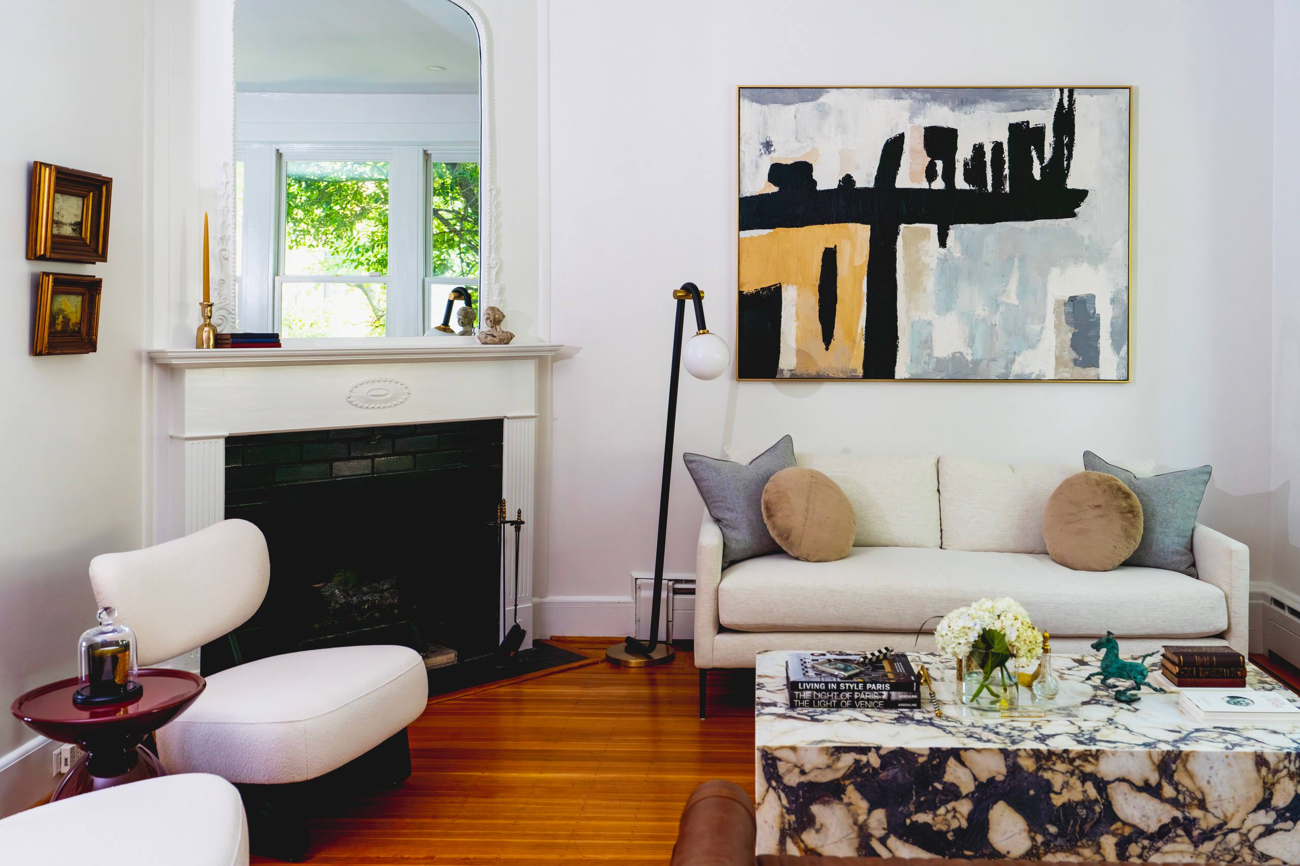 This inviting living room features a harmonious blend of modern elegance and timeless comfort. At the heart of the space, a minimalist beige sofa is paired with two cream lounge chairs, creating a coz