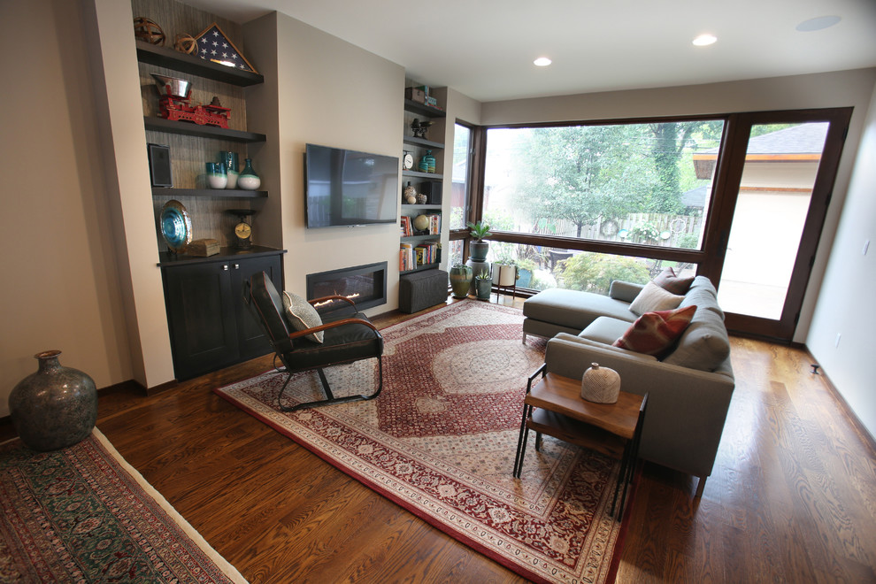 This is an example of a mid-sized eclectic open concept family room in Detroit with a game room, beige walls, dark hardwood floors, no fireplace, a wall-mounted tv and brown floor.