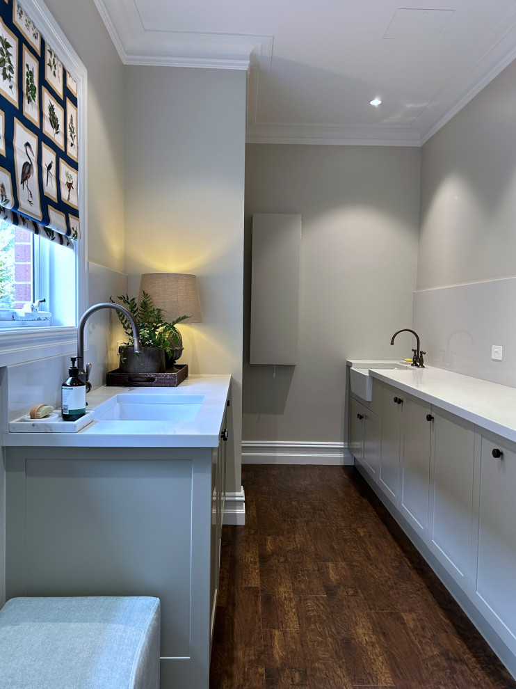 Inspiration for a large modern galley dedicated laundry room in Sydney with an undermount sink, shaker cabinets, green cabinets, marble benchtops, grey splashback, engineered quartz splashback, green walls, dark hardwood floors, a stacked washer and dryer, brown floor, grey benchtop and coffered.