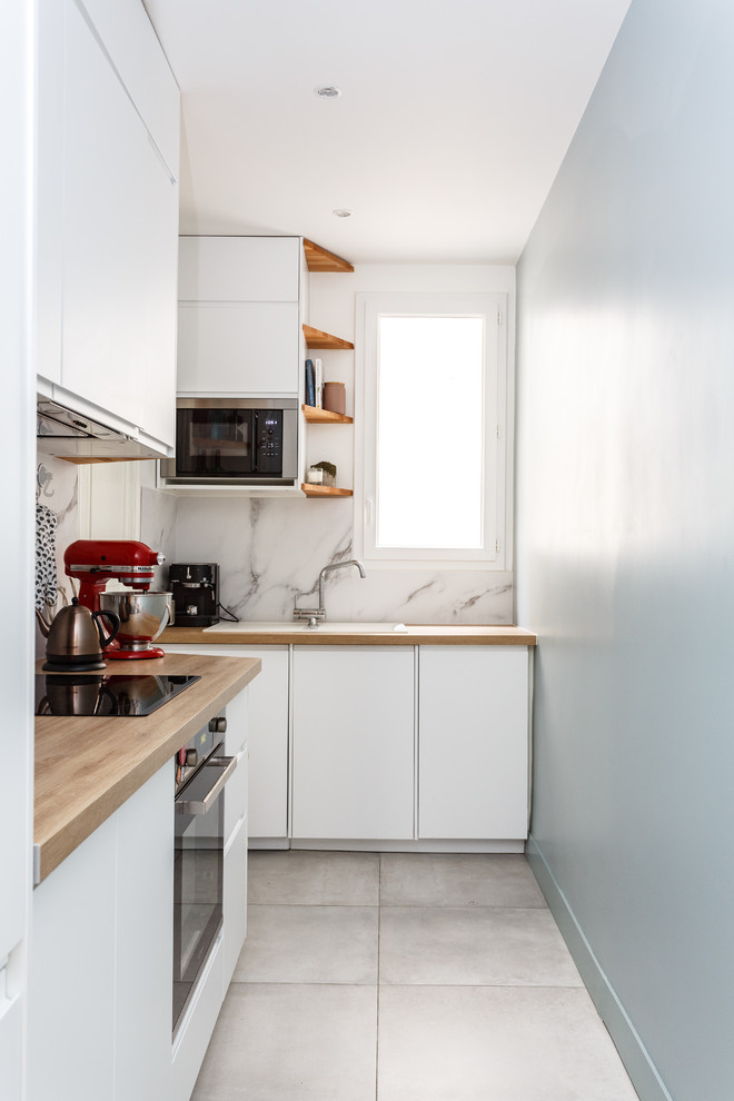 Small modern l-shaped separate kitchen in Paris with a drop-in sink, flat-panel cabinets, white cabinets, wood benchtops, white splashback, marble splashback, stainless steel appliances, ceramic floors, no island, grey floor and beige benchtop.