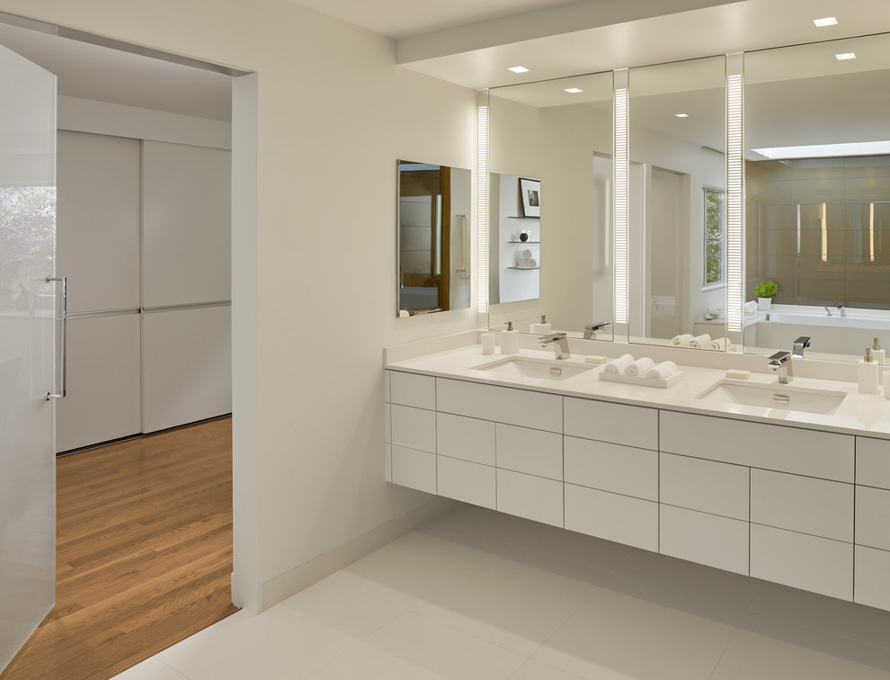 Large contemporary master bathroom in San Francisco with an undermount sink, flat-panel cabinets, white cabinets, white walls, white tile, an alcove shower, porcelain tile, solid surface benchtops, an alcove tub, a wall-mount toilet and porcelain floors.