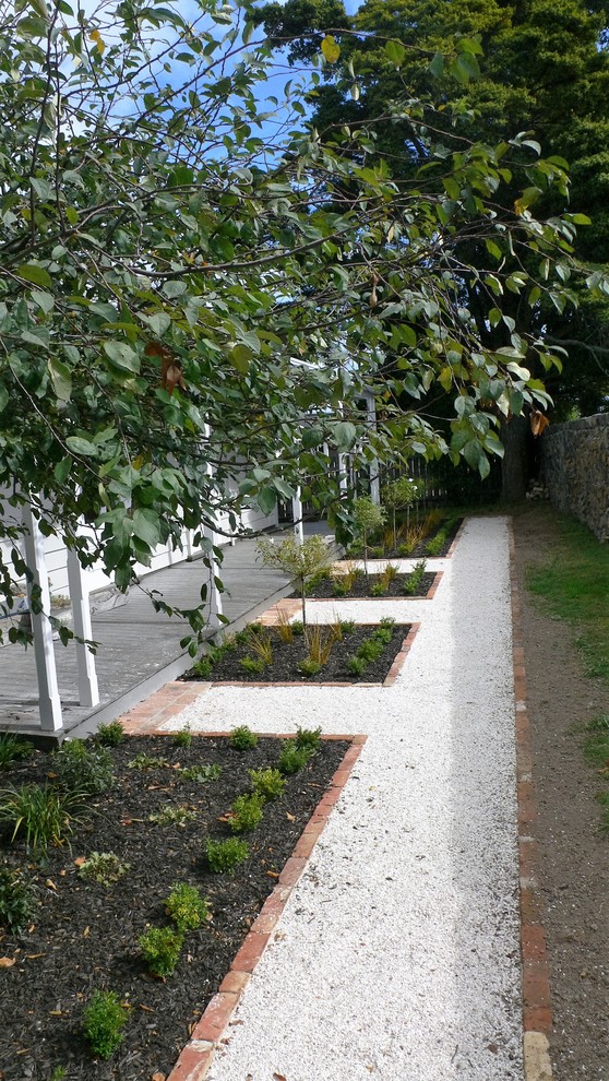 This is an example of a mid-sized traditional front yard full sun formal garden for summer in Auckland with a garden path.