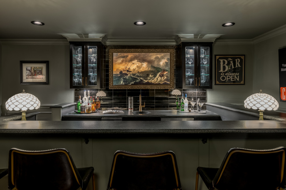 Photo of a large transitional single-wall seated home bar in New York with an undermount sink, glass-front cabinets, black cabinets, soapstone benchtops, black splashback, glass tile splashback, dark hardwood floors, brown floor and black benchtop.
