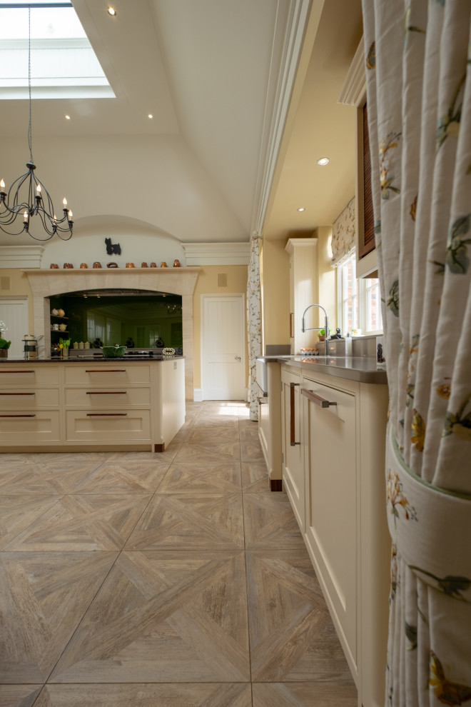 Expansive traditional eat-in kitchen in Hampshire with a farmhouse sink, shaker cabinets, yellow cabinets, granite benchtops, green splashback, glass sheet splashback, panelled appliances, ceramic floors, with island, multi-coloured floor and grey benchtop.