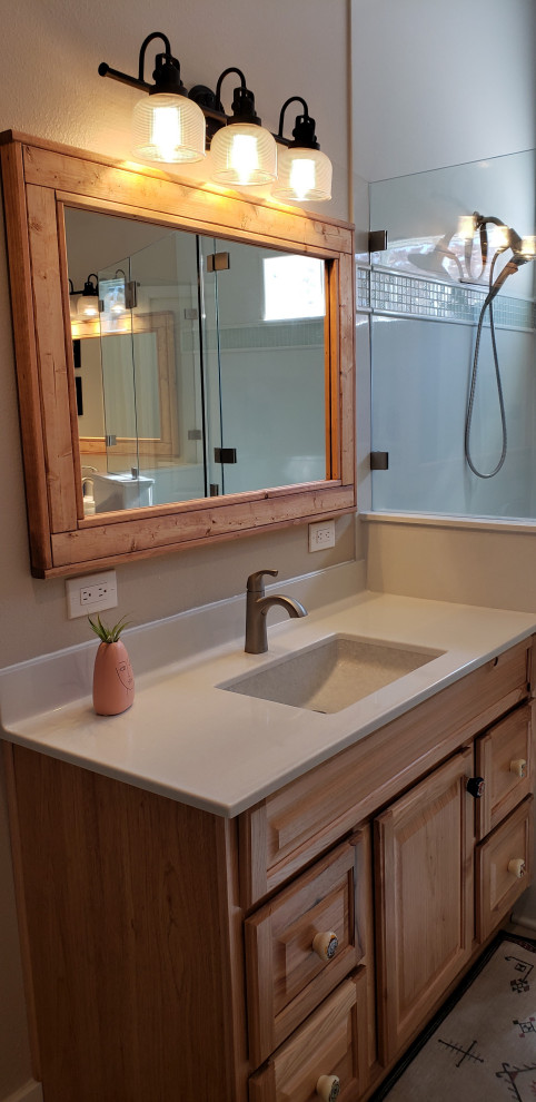 Inspiration for a mid-sized master bathroom in Albuquerque with raised-panel cabinets, light wood cabinets, a corner shower, solid surface benchtops, a hinged shower door, white benchtops, a double vanity and a built-in vanity.