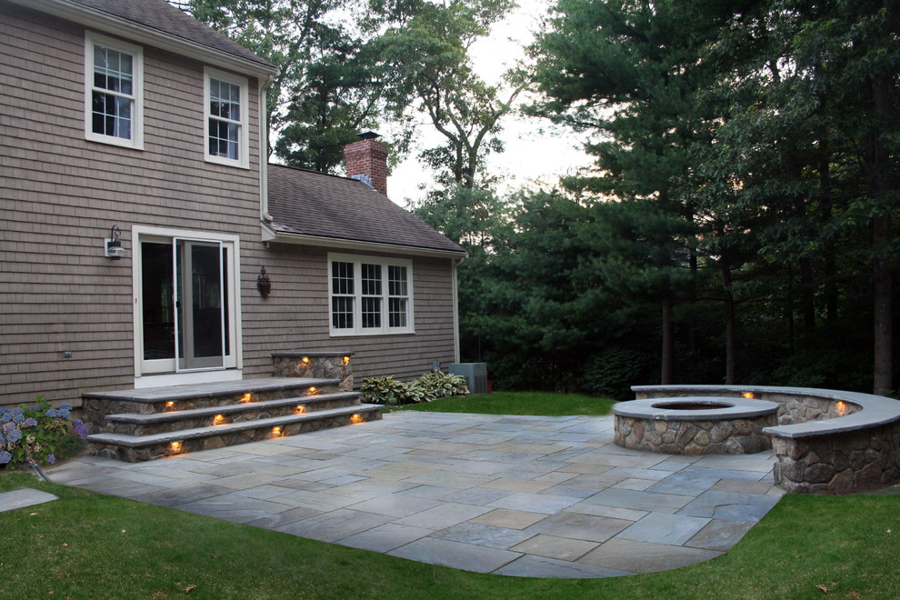 Photo of a traditional backyard patio in Boston with a fire feature and natural stone pavers.