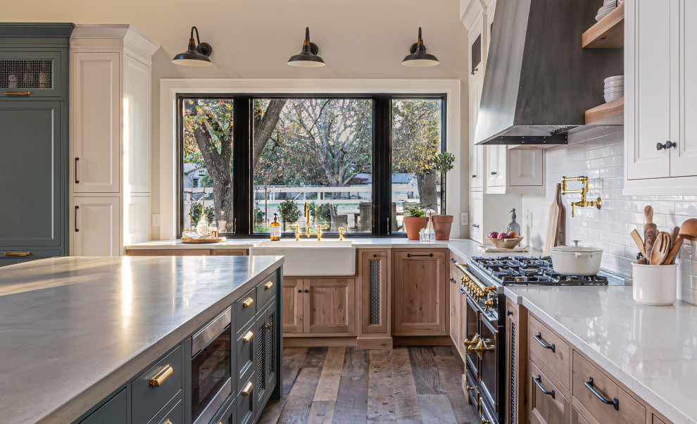 Photo of a large rural l-shaped open plan kitchen in San Francisco with a belfast sink, shaker cabinets, blue cabinets, concrete worktops, white splashback, porcelain splashback, integrated appliances, medium hardwood flooring, an island, brown floors, grey worktops and a vaulted ceiling.