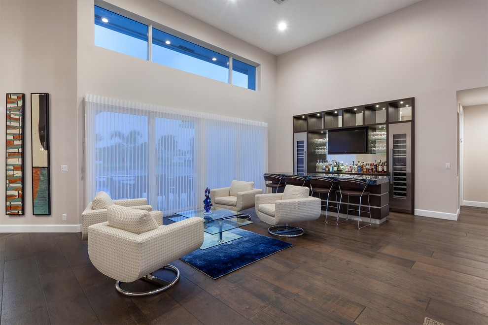 This is an example of an expansive contemporary open concept living room in Miami with a home bar, white walls, dark hardwood floors, a built-in media wall and brown floor.